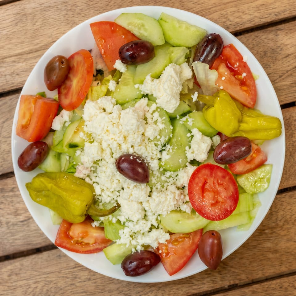 Overhead view of a vibrant Greek salad with feta, olives, tomatoes, cucumbers, and peppers.
