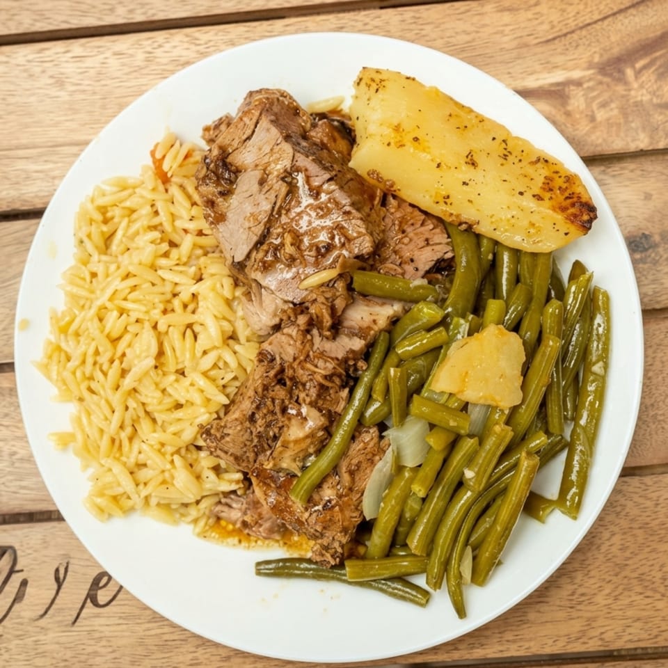A white plate with pot roast, orzo pasta, green beans, and a roasted potato wedge.